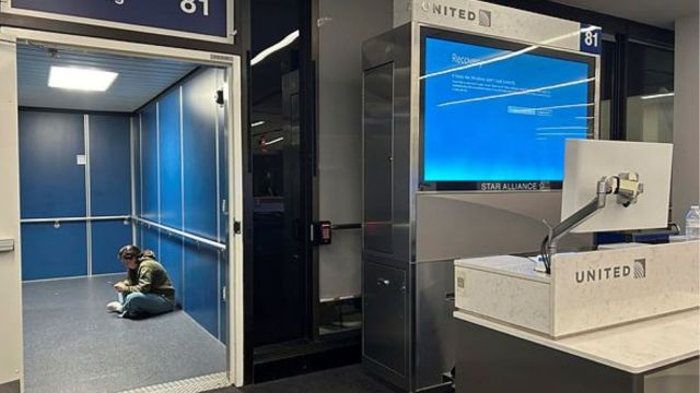 A traveler at Los Angeles International Airport sits in a jetway for a delayed United Airlines flight to Dulles International Airport due to a widespread global technology outage disrupting flights, banks, media outlets and companies around the world