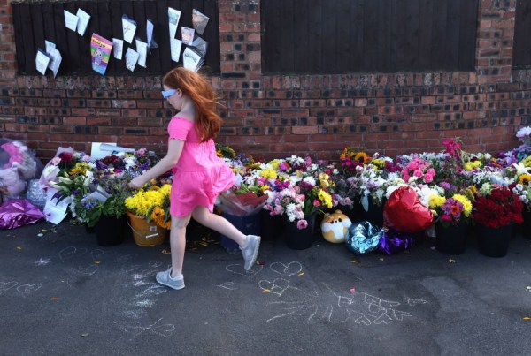 A girl runs past flowers at a makeshift memorial allowing people to pay their respects to the victims of a knife attack, in Southport, Britain August 9, 2024. 