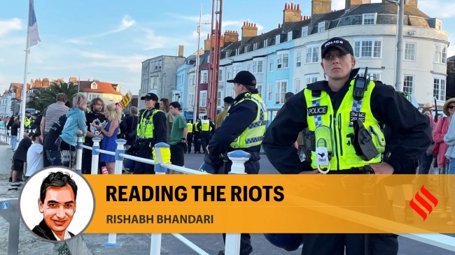 Police warring riot protection equipment patrol the seafront esplanade following an anti immigration protest in Weymouth