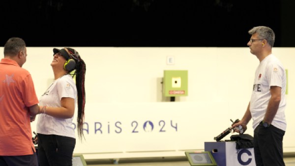 Turkish shooter Yusuf Dikec, right, looks on as Turkey's coach talks to Dikec's teammate Sevval Ilayda Tarhan during a time-out break at the 10m air pistol mixed team final, in Chateauroux, France, at the 2024 Summer Olympics, Tuesday, July 30, 2024. The Turkish team won the silver medal. (AP Photo)