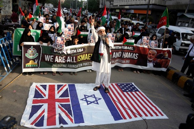 A supporters of the Pakistani Shiite Muslim group 'Imamia Student Organization' and 'Palestine Foundation Pakistan' stands on British, U.S. and Israeli flags in Karachi, Pakistan, Wednesday, July 31, 2024 during a protest to condemn the death of Hamas leader Ismail Haniyeh.