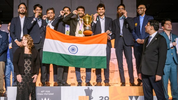 The Indian team celebrates the gold medal in the open section on the podium as chess legends Viswanathan Anand and Susan Polgar look on. (FIDE/Michal Walusza) 