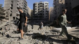 People walk on the rubble at the site of the Israeli airstrike that killed Lebanon's Hezbollah leader Sayyed Hassan Nasrallah on Friday, in Beirut's southern suburbs