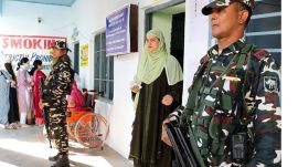 one nation ecurity personnel stand guard as a voter leaves a polling booth after casting vote at a polling station during the first phase of Jammu and Kashmir Assembly elections, in Kishtwar district