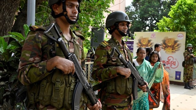 Army soldiers basal   defender  arsenic  Hindu devotees get  to connection    prayers during the Durga Puja festival astatine  a temple successful  Dhaka. (Reuters) bangladesh