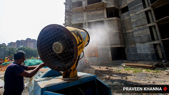 Workers use a Smog Gun to control dust at a construction site in New Delhi. (Express photo by Praveen Khanna)