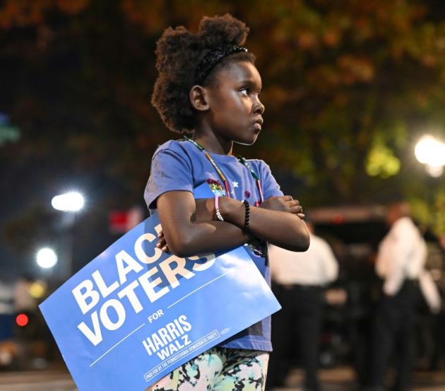A young girl holds a "Black Voters for Harris-Walz" sign outside of Democratic presidential nominee Vice President Kamala Harris' election night watch party at Howard University,