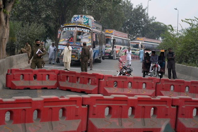 Police officers stand guard on an entry point to motorway leading to Islamabad, which has been closed by authorities due to a planned rally by supporters of imprisoned former Prime Minister Imran Khan's Pakistan Tehreek-e-Insaf party, in Lahore, Pakistan, Saturday, Nov. 23, 2024. (AP Photo/K.M. Chaudary)