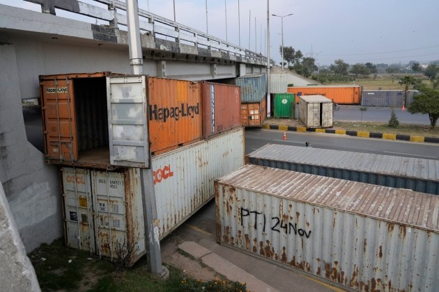Motorcyclists drive on a highway, which partially closed with shipping containers ahead of a planned rally by supporters of imprisoned former Prime Minister Imran Khan's Pakistan Tehreek-e-Insaf party, in Islamabad, Pakistan, Saturday, Nov. 23, 2024. (AP Photo/Anjum Naveed)