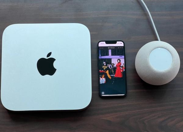 The old-generation Mac Mini next to the iPhone 13 mini and HomePod Mini.