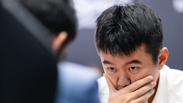 Ding Liren sneaks a peek at his opponent Gukesh in a game of the World Chess Championship in Singapore. (PHOTO: FIDE/Eng Chin An)