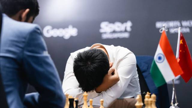 World Champion Ding Liren reacts on the board during Game 6 of the World Chess Championship as Gukesh looks on. (PHOTO: FIDE Flickr via Eng Chin An)