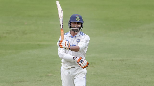 India's Ravindra Jadeja raises his bat as he celebrates after scoring fifty runs during play on day four of the third cricket test between India and Australia at the Gabba in Brisbane, Australia, Tuesday, Dec. 17, 2024. (AP Photo)