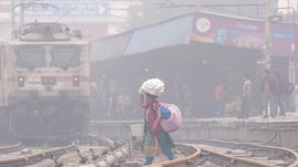 A woman crosses railway tracks amid fog on a cold winter day, in New Delhi