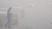 A man crosses a road amid dense fog in New Delhi,