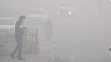 A man crosses a road amid dense fog in New Delhi,