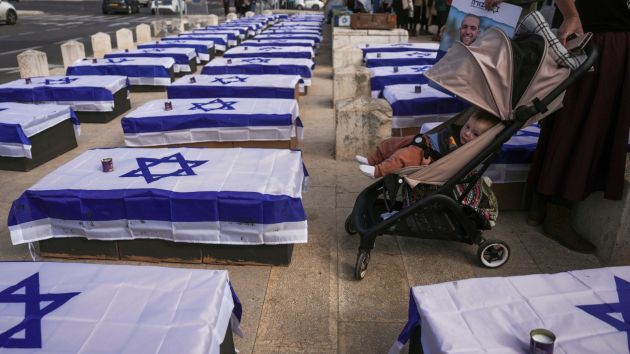 People stand by coffins lining a street and covered with Israeli flags that are meant to symbolize the price Israel will pay for agreeing to a ceasefire with Hamas in a demonstration against the deal staged by a group representing families of Israelis killed during the war in Gaza. (Photo: AP)