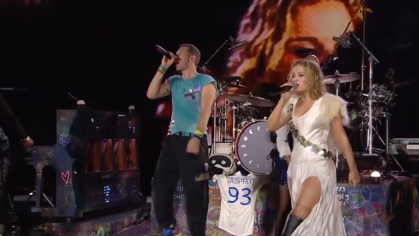 A signed India jersey of Jasprit Bumrah is displayed on stage as Coldplay's Chris Martin performs at Ahmedabad's Narendra Modi Stadium. (Screenshot: Hotstar)