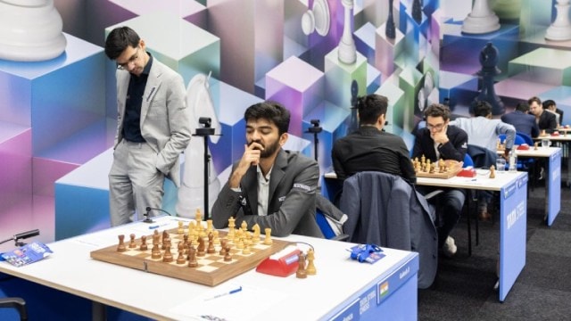 Gukesh contemplates his next move in the round 9 game against Leon Luke Mendonca as Anish Giri steals a glance. (Photo: Jurriaan Hoefsmit via Tata Steel Chess)