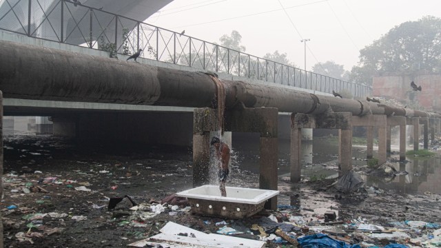 Image of man bathing under leaking pipeline in Delhi (Image source: @jinxiyu/Reddit)