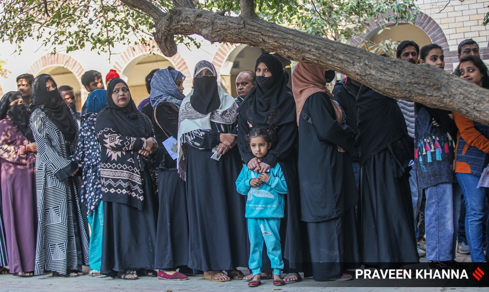 People queue-up to vote outside a polling station in Delhi's Jafrabad, Seelampur constituency, on Wednesday