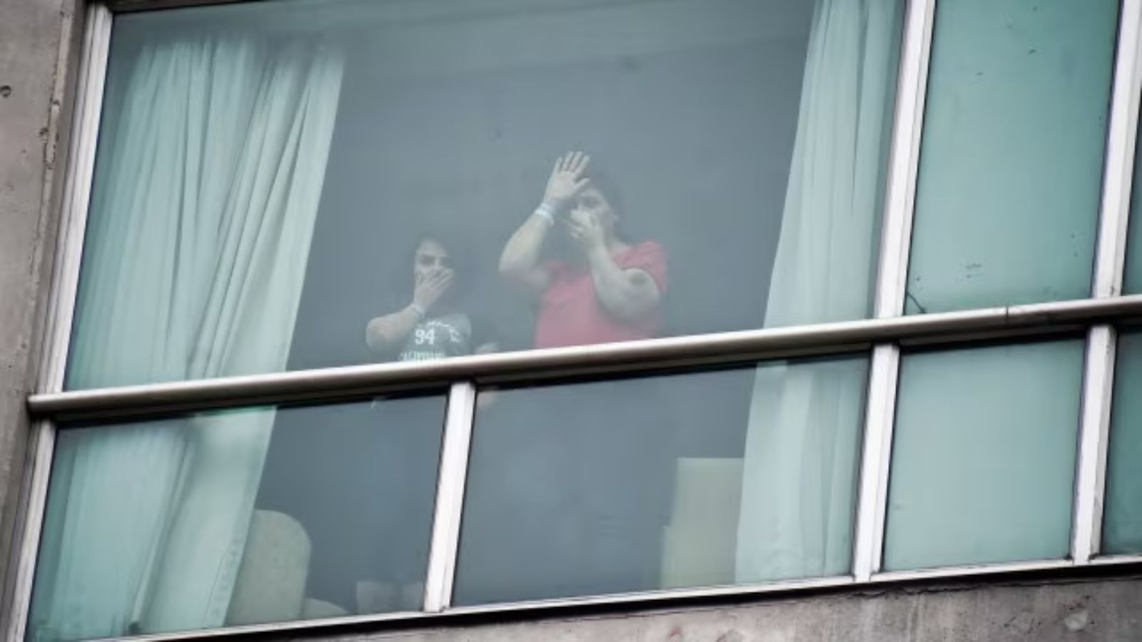Migrants deported from the United States wave to the press from inside a hotel in Panama City, Wednesday, Feb. 19, 2025. (AP Photo)