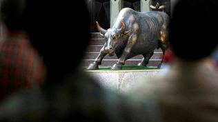 Budget 2025 Share Market Live: stock market A bronze sculpture of a bull is seen on the premises of the Bombay Stock Exchange (BSE) building as people watch a large screen displaying India's benchmark share index on the facade of the building in Mumbai. (Reuters File)