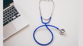 doctor gbs pune sthethoscope against plain background and part of a laptop seen