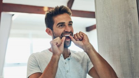 Shot of a cheerful young man flossing his teeth while looking at his reflection in the mirror at home, flossing, oral hygiene, oral health, stroke, stroke and flossing, indian express