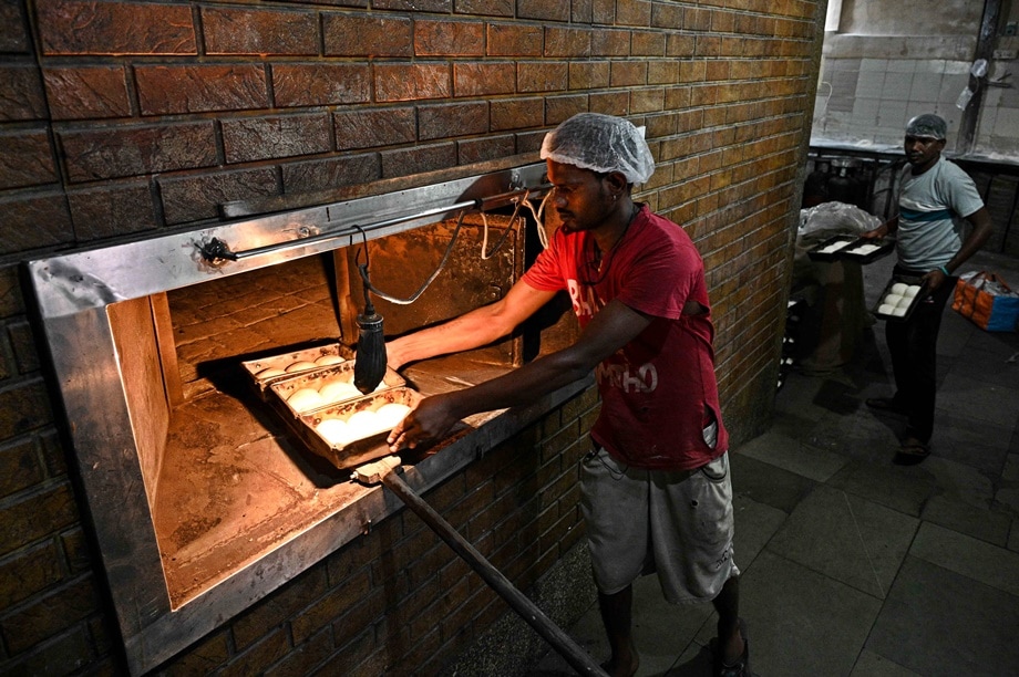 A workers places ladi pav for baking in an oven in the New Edward Bakery, Fort, in Mumbai.