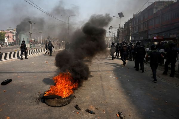 Riot police personnel move past a burning tyre during a protest by pro-monarchist demonstrators demanding the restoration of Nepal's monarchy, which was abolished in 2008, saying the governments have failed to make any significant changes, in Kathmandu, Nepal, March 28, 2025. REUTERS/Navesh Chitrakar