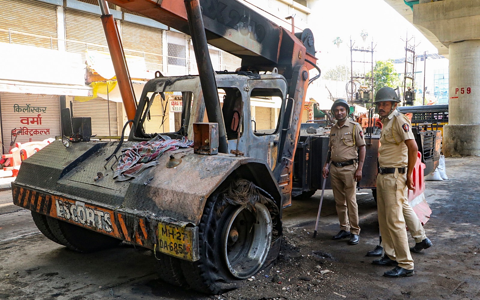 Police personnel near the remains of a vehicle that was torched during violent clashes in Nagpur