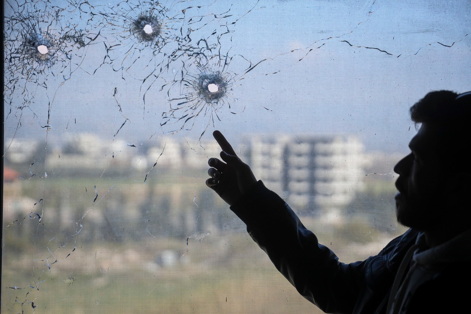 A nurse points to bullet holes in a window following the recent wave of violence between Syrian security forces and gunmen loyal to former President Bashar Assad in Syria