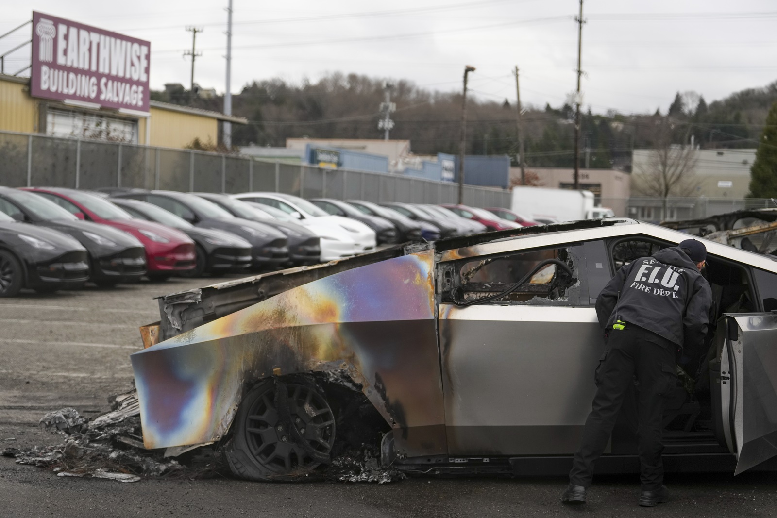 A member of the Seattle Fire Department inspects a burned Tesla Cybertruck at a Tesla lot in Seattle