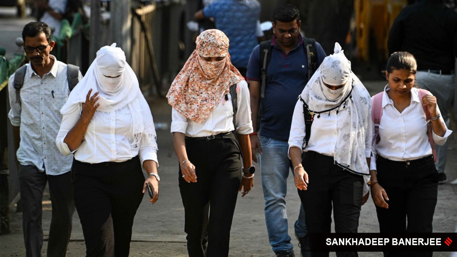 Women with their faces fully wrapped in scarves as a protection from the heat, walk along a street, at Bandra in Mumbai on Thursday. (Express Photo by Sankhadeep Banerjee)