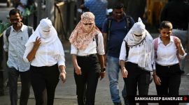 Women with their faces fully wrapped in scarves as a protection from the heat, walk along a street, at Bandra in Mumbai on Thursday. (Express Photo by Sankhadeep Banerjee)