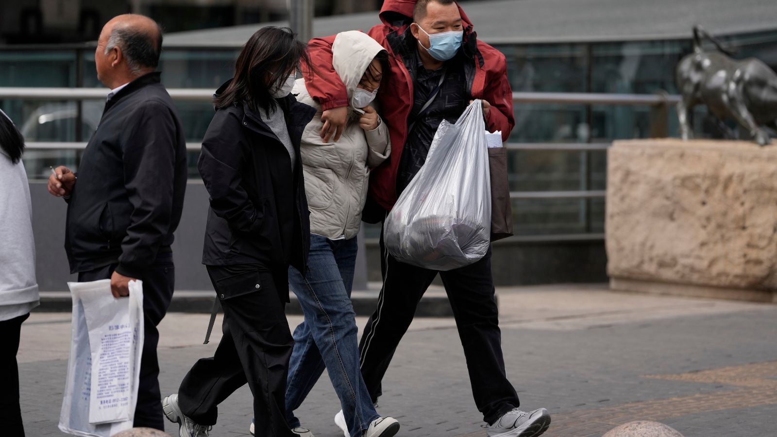 Residents walk against strong winds in Beijing, China, Saturday, April 12, 2025. (AP Photo/Ng Han Guan)