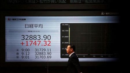 A man walks past an electronic screen displaying Japan's Nikkei share average outside a brokerage in Tokyo