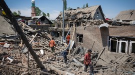 People walk through the rubble of the home of a terrorist that was destroyed at Murran village in Pulwama, South Kashmir, on Saturday