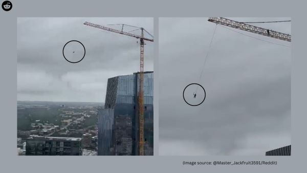 The footage captures a man casually swinging from a construction crane high above downtown Austin