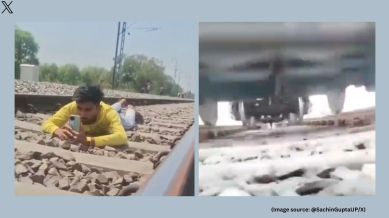 In the video, the man is seen lying on his stomach, holding a mobile phone, and waiting for a train to pass over him (Image source: @SachinGuptaUP/X)
