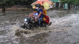 no title set Commuters wade through a waterlogged road (Express/Praveen Khanna)