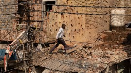 A man walks amid debris on the roof of a damaged house, following Pakistan's shelling in Jammu region on Saturday