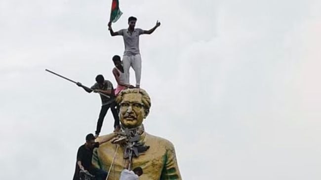 People climb the statue of Sheikh Mujibur Rahman at the Bijoy Sarani area, as they celebrate the resignation of the Prime Minister Sheikh Hasina in Dhaka, Bangladesh.
