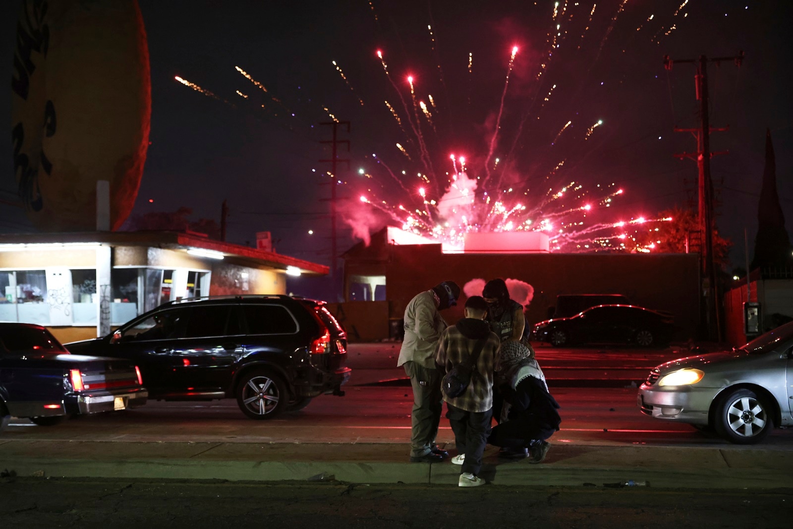 Protesters attempt to light a Molotov cocktail as a firework explodes during a protest in Compton, California on Saturday after federal immigration authorities conducted operations
