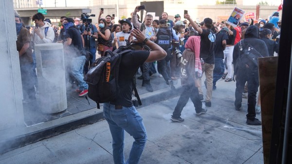 People react as a Department of Homeland Security officer shoots pepper balls during a protest in Los Angeles on Friday