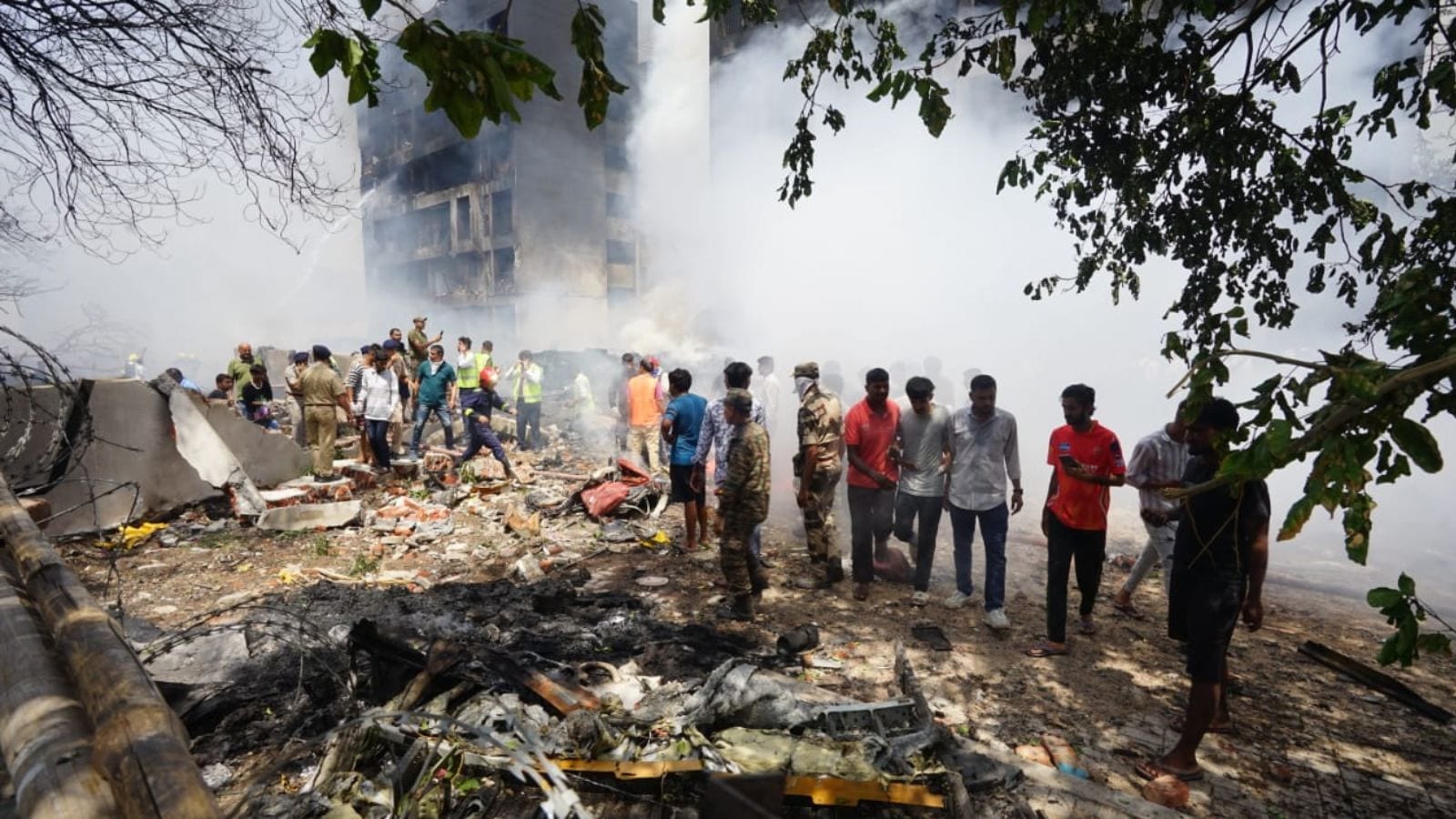 People stand around debris at the site of an airplane that crashed in India's northwestern city of Ahmedabad in Gujarat state