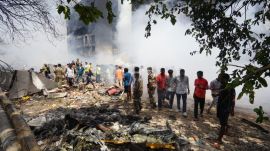 People stand around debris at the site of an airplane that crashed in India's northwestern city of Ahmedabad in Gujarat state