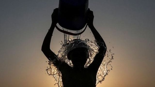 A boy pours water over himself for respite from the scorching heat,