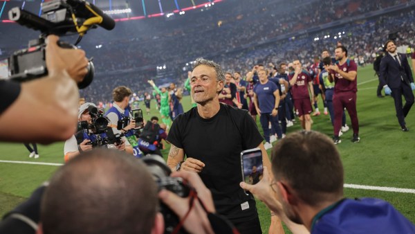 Luis Enrique, was in his usual black T-shirt and set about parading the Champions League trophy on the pitch when the PSG fans unfurled the tifo banner (AP Photo)